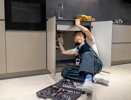 A technician repairing a kitchen sink